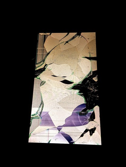 A massive amount of destruction on a display 
is portrait against a black background. The screen is shattered, with a network of cracks spreading across its entire surface. The shattered areas reveal a mosaic of colors, including beige, white, and purple, interspersed with black fragments where the screen is completely broken, shattered, kaput. The cracks are highlighted with green outlines